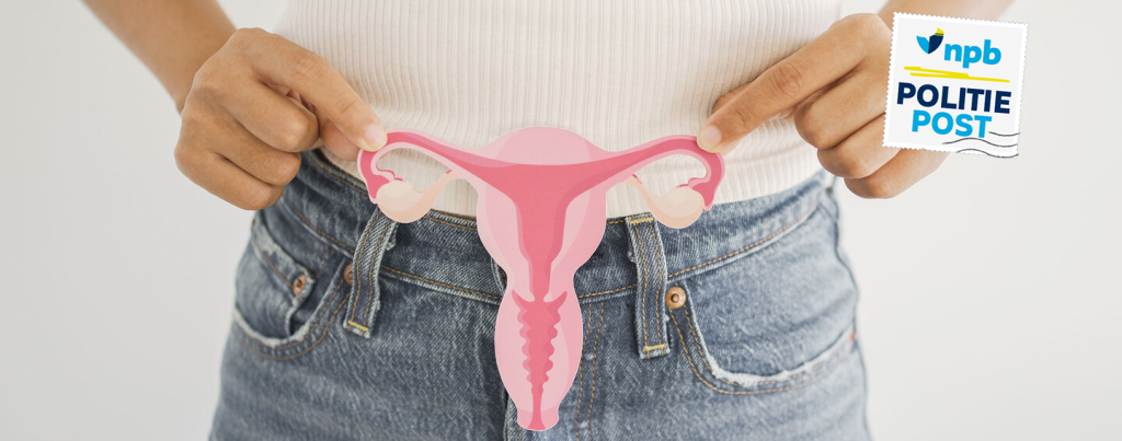Person holding a pink uterus-shaped cutout in front of their jeans, illustrating female reproductive anatomy for health education.
