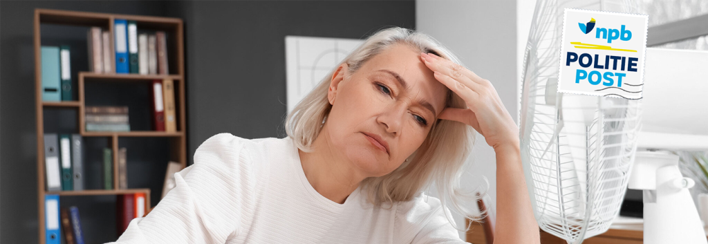 Tired woman resting her head on her hand at a desk in an office, with a bookshelf and a standing fan nearby, stamp reading 'NPB Politie Post' in the corner.