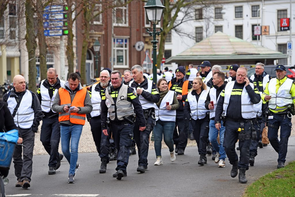 Group of people in high-visibility vests walking together down a city street during a march or event.