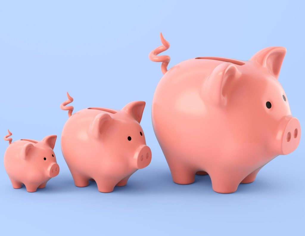Group of pink piggy banks of different sizes standing on a blue surface against a light blue background.