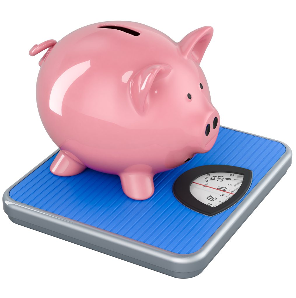 Pink piggy bank perched on a blue analog bathroom scale, illustrating savings and weight.